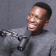 Paystack CEO Shola Akinlade smiling, with a podcast microphone in front of him